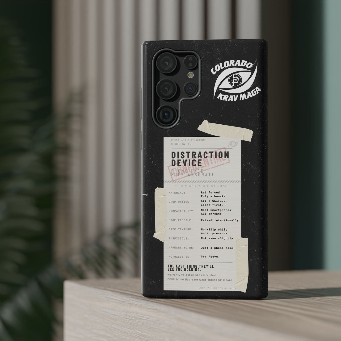Immortal Krav Maga Distraction Device phone case, black reinforced polycarbonate with tactical label and Colorado Krav Maga logo.